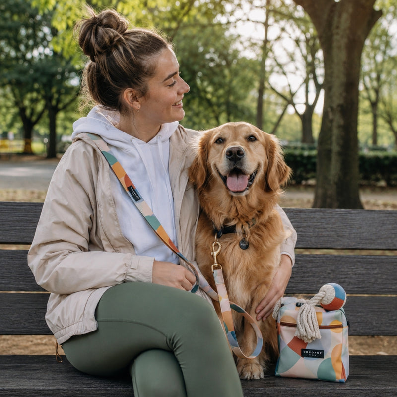 smiling woman sitting on a park bench with her golden retriever